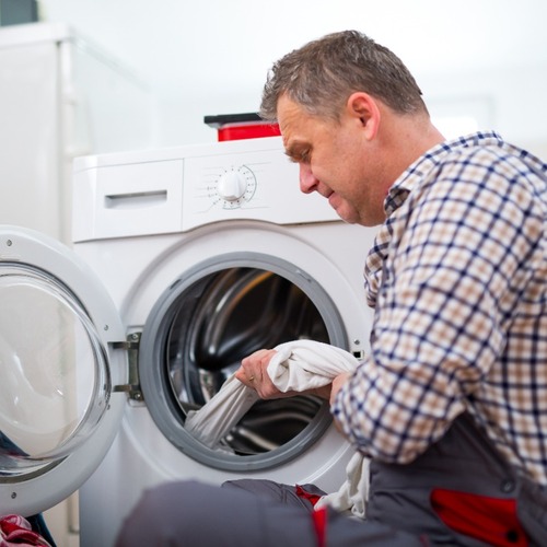 A Technician Repairs a Washer.